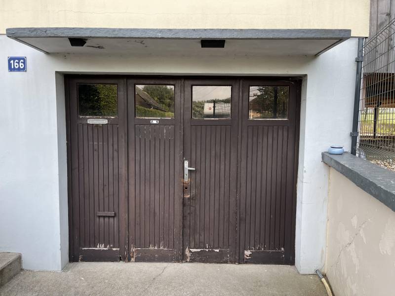 Artisan menuisier pour le remplacement d'une porte de garage en bois par une porte de garage en aluminium isolée en trois panneaux rainurés avec portillon de chez DC PRODUCTION, secteur FECAMP (76)